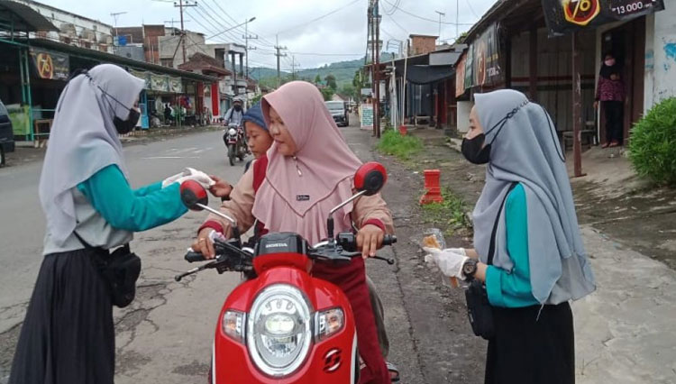 Mahasiswa KSM Tematik Unisma Malang berbagi masker di sepanjang jalan desa Gampingan. (FOTO: AJP TIMES Indonesia)