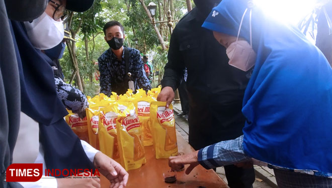 Warga mencelupkan jari ke cairan tinta setelah mendapatkan jatah minyak goreng. (Foto: Yupi Apridayani/TIMESIndonesia)