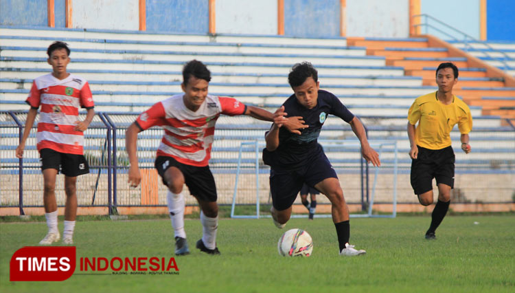 Penyerang tim sepakbola Lamongan (biru tua) berusaha melepaskan diri dari kawalan pemain Kabupaten Bangkalan, dalam laga uji coba di Stadion Surajaya, Senin (28/3/2022). (FOTO: MFA Rohmatillah/ TIMES Indonesia)