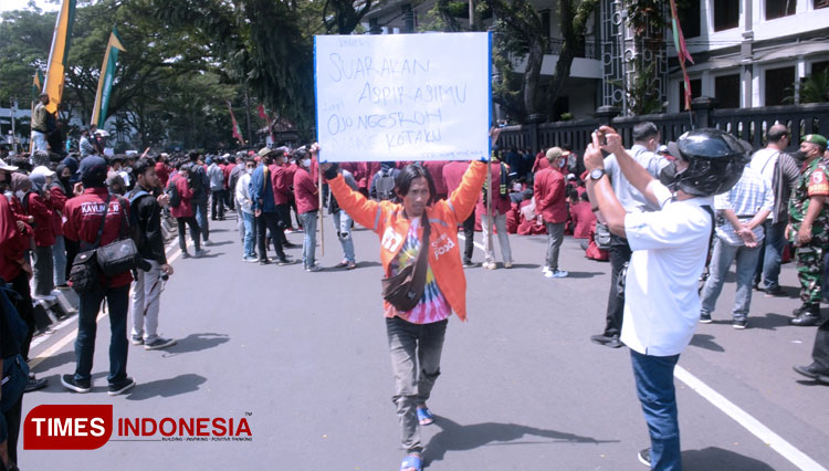 Pengemudi makanan online saat mengeliling lokasi demo dengan membentangkan poster perdamaian di sekitar Alun-Alun Tugu Malang. (FOTO: Adhitya Hendra/TIMES Indonesia)