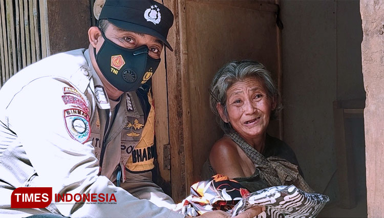 Bripka Latip utomo saat berikan sepasang baju dan jarik buat lebaran nanti kepada mbah Tomblok Wandiem (FOTO: Rojihan/TIMES Indonesia)