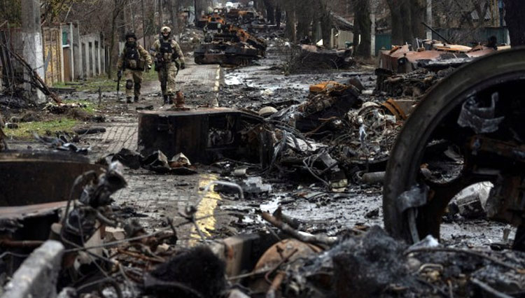 Tentara berjalan di tengah tank Rusia yang hancur di Bucha, di pinggiran Kyiv, Ukraina, Minggu, 3 April 2022.(FOTO: AP)