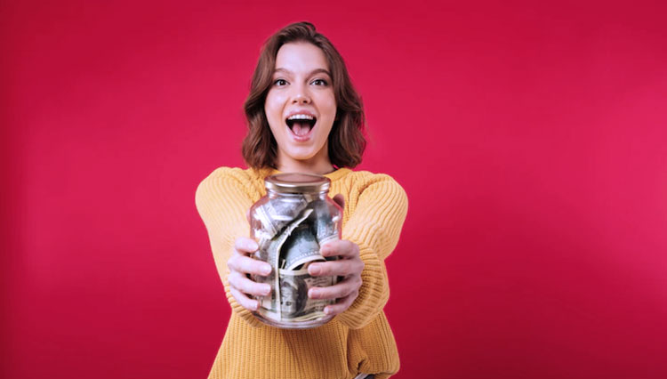 a girl holding a jar of her saving. (Photo: Freepik)