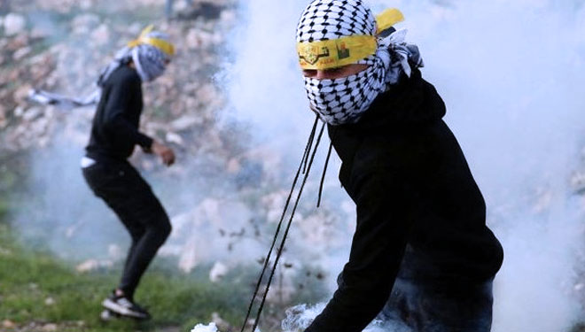 Seorang demonstran Palestina melemparkan kembali gas air mata yang ditembakkan pasukan Israel. (Mohamad Torokman/Reuters/Antara)