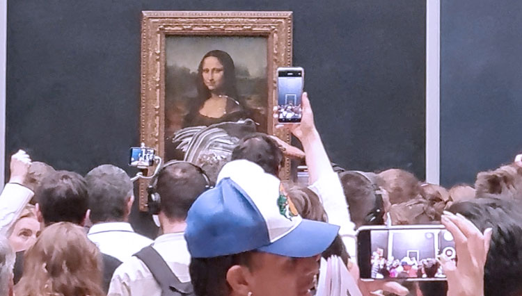 Pengunjung mengambil foto dan video lukisan Mona Lisa setelah kue dioleskan pada kaca pelindung di Museum Louvre di Paris. (FOTO: Al Jazeera/Reuters)