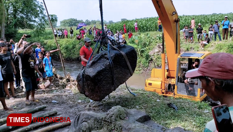 Pengangkatan Arca Kepala Kala dengan menggunakan alat berat dan disaksikan ratusan orang warga. (FOTO: Canda Adisurya/TIMES Indonesia)