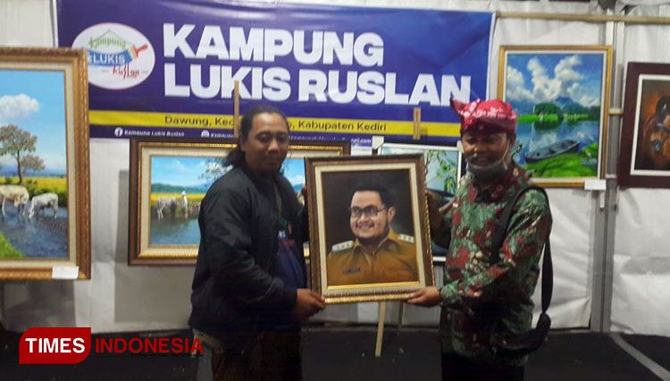 Pelukis Kusharyono menyerahkan lukisan sosok Bupati Kediri Hanindhito Himawan Pramana (Mas Dhito) kepada Kepala Disparbud Kabupaten Kediri, Sabtu (25/6/2022) malam. (Foto: Yobby/TIMES Indonesia).