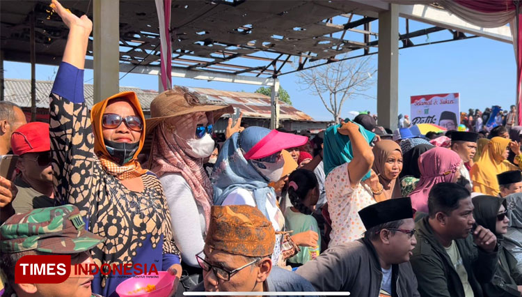 Seorang warga menaburkan beras kuning ke kerumunan warga yang menyaksikan gelaran petik laut. (Foto: M. Ishomuddin/TIMES Indonesia)