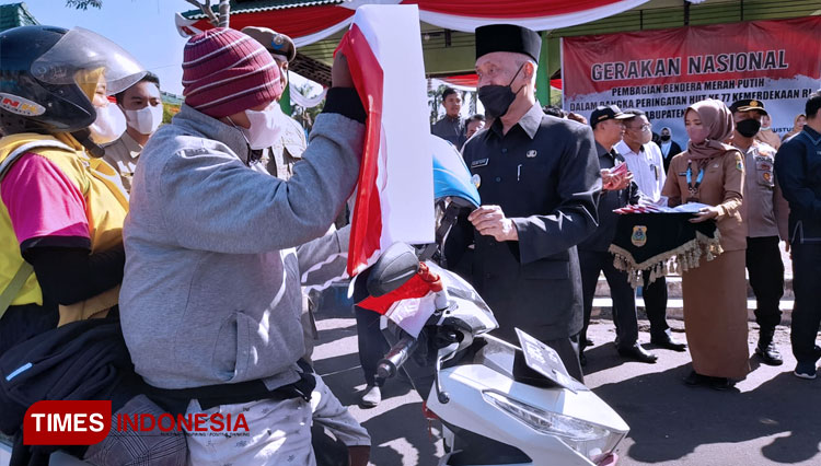 Bupati Bondowoso membagikan Bendera Merah Putih kepada sejumlah pengendara yang melintas di Alun-Alun RBA Ki Ronggo (FOTO: Moh Bahri/TIMES Indonesia)
