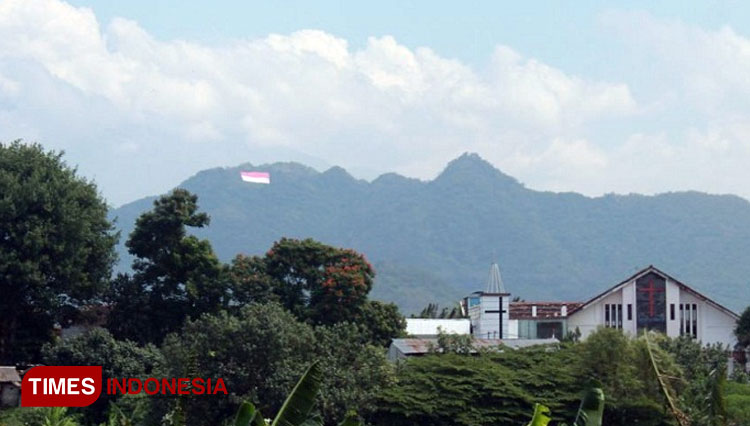 Bendera Merah Putih Raksasa Terbentang di Gunung Klotok, Kota Kediri dilihat dari kejauhan. (Foto: Yobby/TIMES Indonesia)