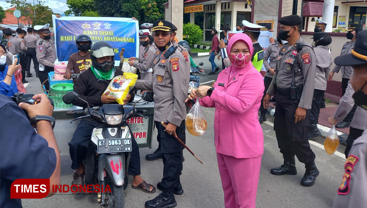 Kapolres Bontang AKBP Yusep Dwi Prasetya bersama istri membagikan paket sembako bagi pengemudi ojol. (Foto: Kusnadi/TIMES Indonesia)