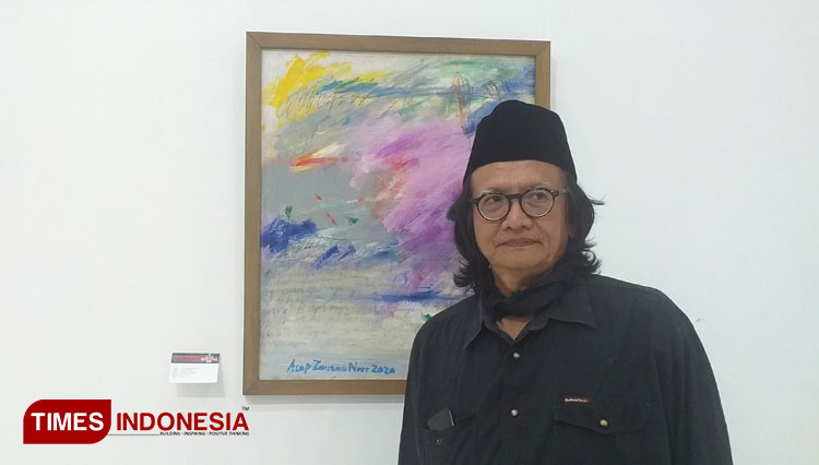 Acep Zamzam Noor berfoto didepan karya lukisnya yang dibuat pada tahun 2020 (Foto: Megha Nugraha/Times Indonesia)