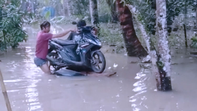 Seorang warga yang rumahnya terdampak banjir mengamankan motor menggunakan peralatan seadanya. (Foto: TAGANA Pangandaran)