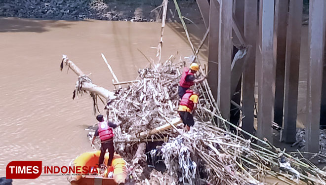 Tumpukan sampah yang menyangkut di tiang pancang Jembar dibersihkan petugas gabungan dari BPBD, Polres dan Dishub Kota Banjar dibantu tim relawan Jaber dan BAZNAS. (Foto: Susi/TIMES Indonesia)