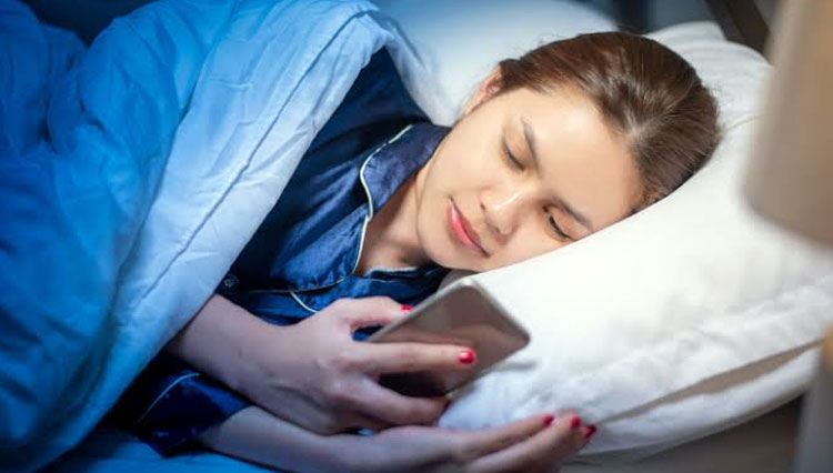 Ilustrasi - bermain HP sebelum tidur. (foto: Shutterstock/Thanakorn.P)