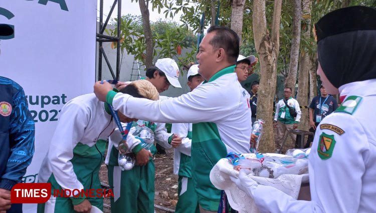 Sekretaris KONI Kab Bandung Yana Mulyana mengalungkan medali untuk atlet cabor panjat tebing Kab Bandung. (Foto: Iwa/TIMES Indonesia)