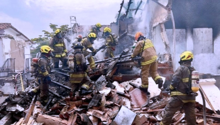 Petugas pemadam kebakaran bekerja di lokasi di mana sebuah pesawat ringan jatuh, menyebabkan delapan orang tewas di lingkungan Belen Rosales di Medellin, Kolombia.(FOTO: RTL Today/AFP)
