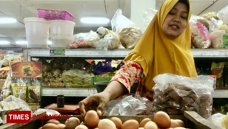Suyatmi, salah satu pedagang sembako di Pasar Besar Ngawi menunjukkan telur ayam negeri yang naik harganya. (FOTO: Miftakul/TIMES Indonesia)