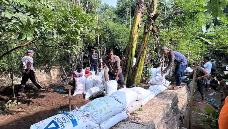 Warga Desa Tambakrejo, Kecamatan Tongas, Kabupaten Probolinggo membuat tanggul darurat di tepi Sungai Laweyan, Jumat, 2 Desember 2022 untuk mencegah banjir. (Foto: Diskominfo)