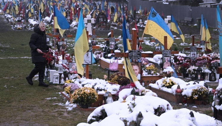 Seorang wanita terlihat mengunjungi makam tentara Ukraina pada Hari Martabat dan Kebebasan di Pemakaman Lychakiv di Lviv. (FOTO: Al Jazeera/AFP)