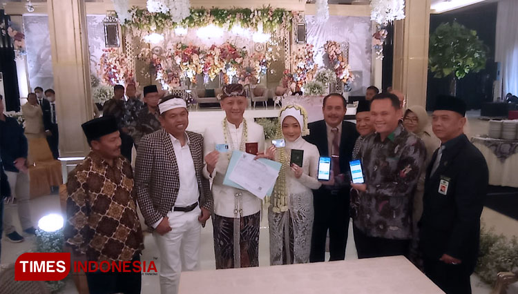 Pj. Walikota Tasikmalaya Cheka Virgowansyah menyerahkan kartu keluarga kepada Briptu M.Ikbal Prasetyo dan dr.Selma Hanifa yang digelar di Graha Asia Plaza, Minggu (13/12/ 2022) (FOTO: Harniwan Obech/TIMES Indonesia)
