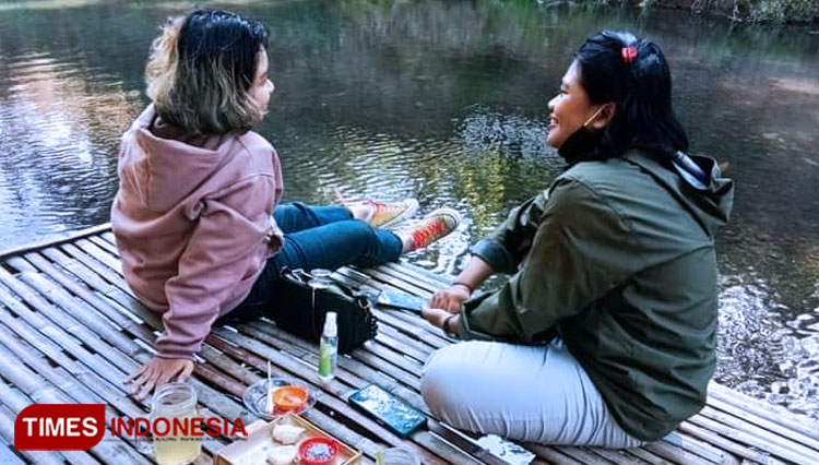 Wisatawan sedang menikmati kuliner sambil merendam kaki di sungai. (Foto : Totok Hidayat/TIMES Indonesia)