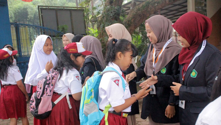 Mahasiswa KKM 225 UIN Malang menyambut kedatangan siswa masuk sekolah di hari pertama Senin, 2 Januari 2023. (FOTO: AJP TIMES Indonesia)