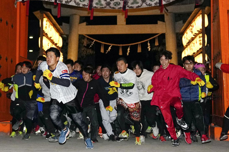 Para pria menerobos gerbang Kuil Nishinomiya di Prefektur Hyogo pada awal lomba. 