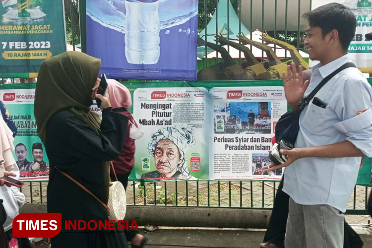 Jemaah 1 Abad NU yang tidak sengaja terpotret Selfi di depan E-Koran TIMES Indonesia sepanjang 100 meter di Gelora Delta Sidoarjo, Selasa (7/2/2023) (Foto: Yusuf Arifa'i/TIMES Indonesia)
