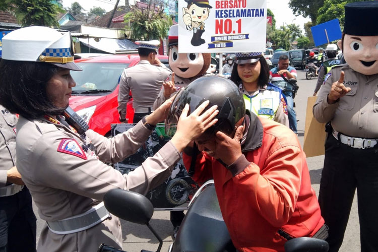 Kasatlantas Polres Malang AKP Agnis J Manurung ketika memberikan helm kepada pengendara sepeda motor. (Foto : Humas Polres Malang)