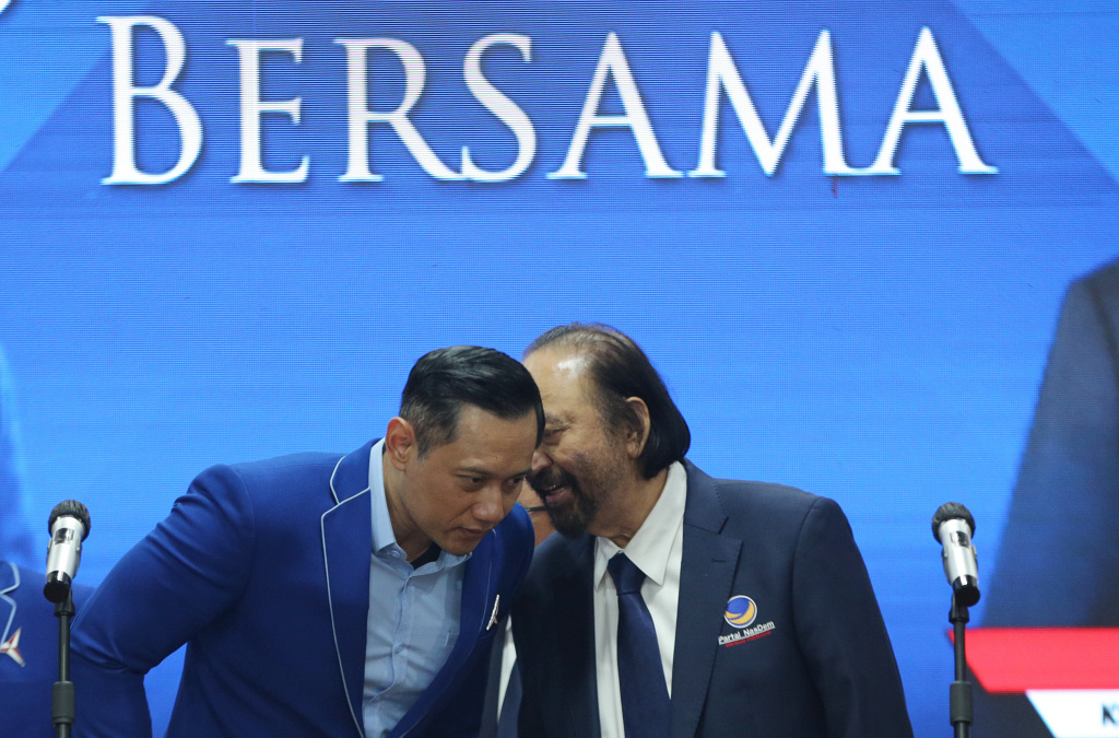Ketua Umum Partai NasDem Surya Paloh berbisik kepada Ketua Umum Partai Demokrat Agus Harimurti Yudhoyono saat jumpa pers