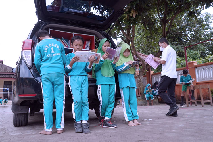 Anak-anak saat membaca buku bacaan yang dibawa mobil operasional Disdik Kabupaten Kediri. (FOTO: Dok. Pemkab Kediri) 