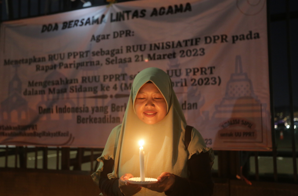 Seorang aktivis sipil membawa lilin saat aksi di depan gedung DPR RI, Senayan, Jakarta, Rabu (16/3/2023).