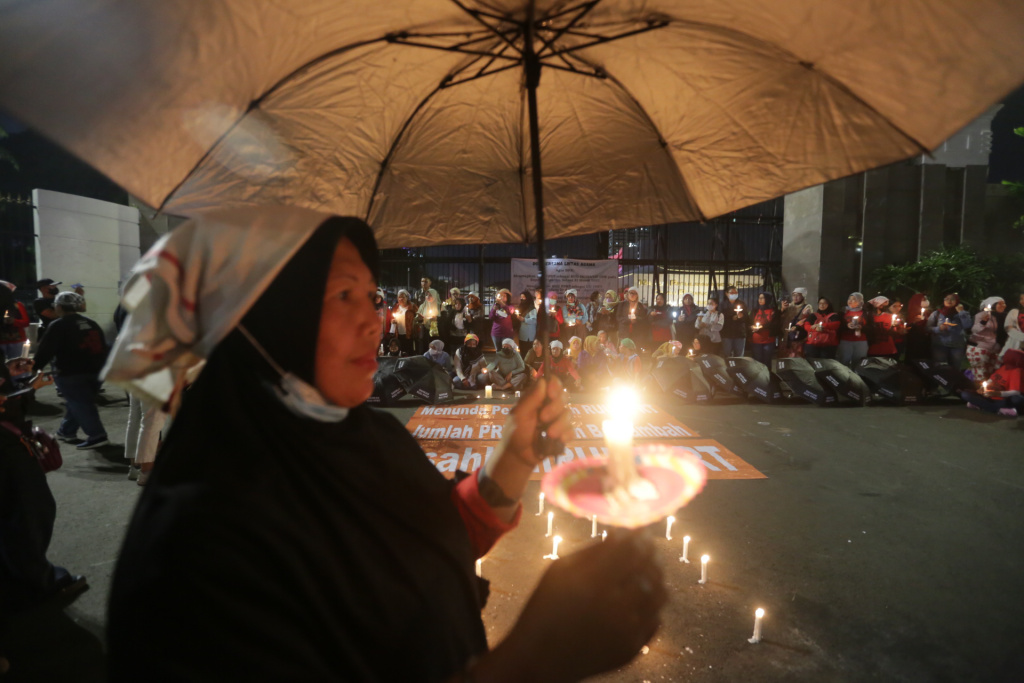 Seorang aktivis sipil membawa lilin saat aksi di depan gedung DPR RI, Senayan, Jakarta, Rabu (16/3/2023).
