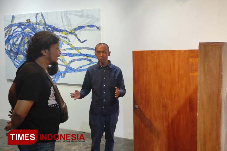 Seniman tunggal Arya Sudrajat (kanan), menjelaskan karya-karyanya kepada publik yang datang ke RedBase Foundation. (Foto: Hendro S.B/TIMES Indonesia) 