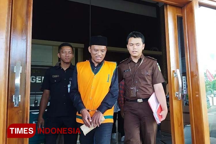 Kades Bangunsari Edy Suwito (42) berpeci dan rompi orange dengan tangan diborgol diringkus Kejari Pacitan atas dugaan tindak pidana korupsi pengelolaan APBDes. (FOTO: Yusuf Arifai/TIMES Indonesia) 