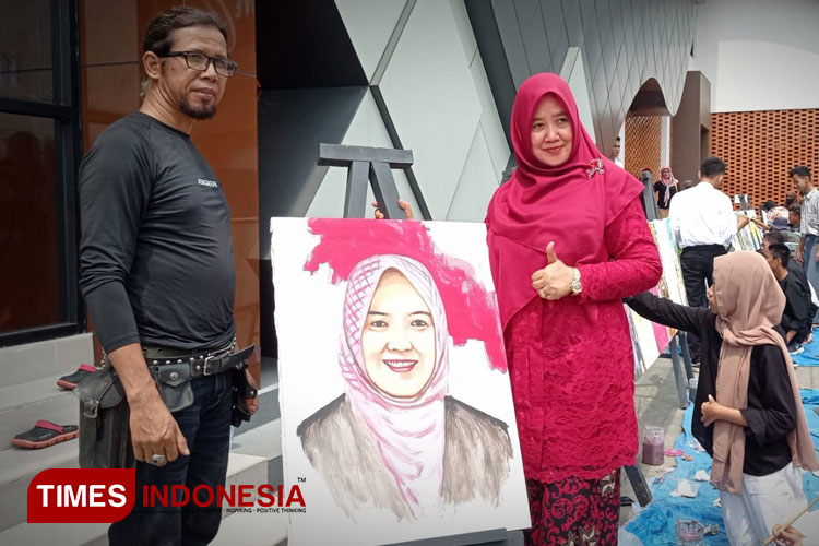 Kadisdik Majalengka, Hj. Lilis Yuliasih berpose di samping lukisan dirinya hasil karya Ketua Peka, Ade Realism. (FOTO: Hendri Firmansyah/TIMES Indonesia)