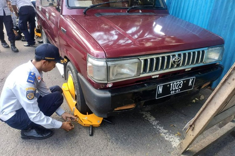 Personel Dishub Kota Malang saat melakukan penggembokan dan penertiban kendaraan yang parkir sembarangan. (Foto: Dok. Dishub Kota Malang/TIMES Indonesia)
