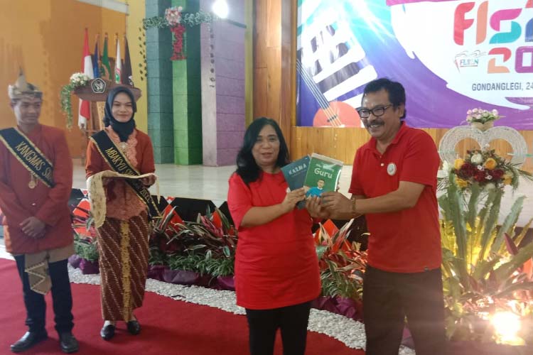 Anny Saulina Kepala cabang dinas pendidikan Kabupaten Malang Propinsi Jawa Timur saat menerima buku dari Teguh Pramono Ketua Panitia FLS2N tingkat Kabupaten Malang di SMA Negeri 1 Gondanglegi dalam pembukaan Festival Lomba Seni Siswa Nasional.