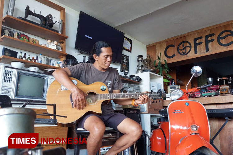 Owner Kedai Ndeso, Edy Sunarto, sedang bermusik panggung musik di kedai vintage miliknya yang berlokasi di Jalan Raya Pakel, Desa Pakel, Kecamatan Licin, Banyuwangi, Jawa Timur. (FOTO : Anggara Cahya /TIMES Indonesia)