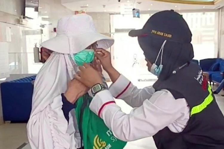 Petugas haji membantu jemaah memakai masker untuk menghadapi cuaca panas dan berdebu. (FOTO: MCH 2023)
