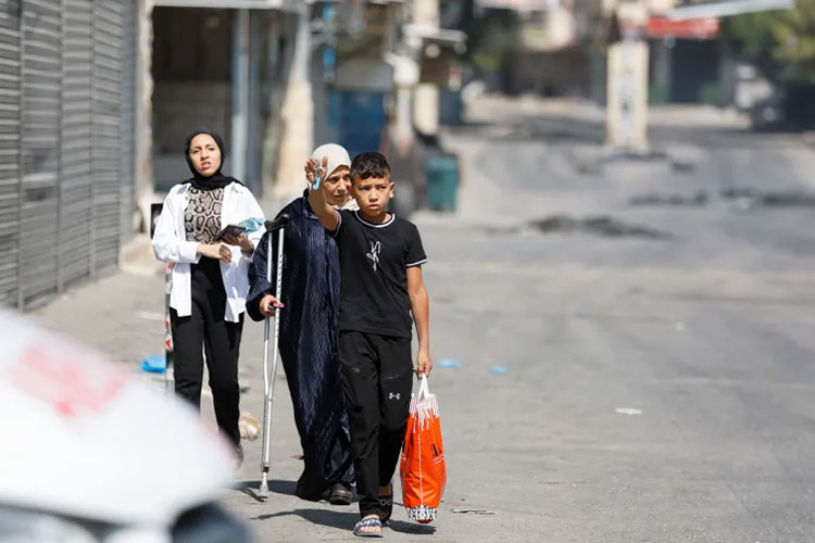 Warga Palestina berjalan di jalan selama serangan militer Israel di Jenin, Tepi Barat yang diduduki Israel pada 3 Juli 2023. (FOTO: Al Jazeera/Reuters)