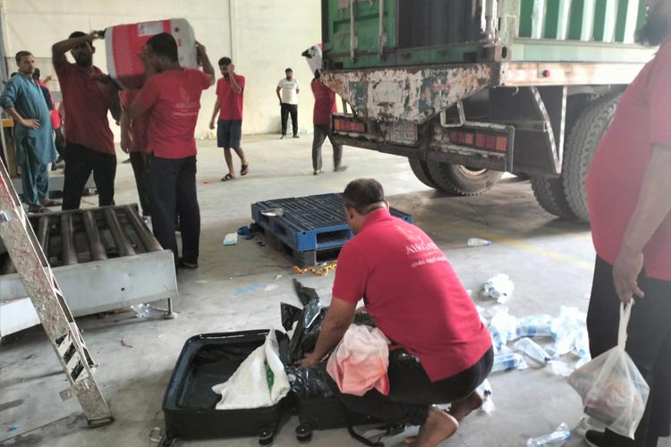 Petugas bandara membongkar koper milik jemaah haji yang kedapatan membawa air zamzam di dalam koper. (foto: MCH 2023) 