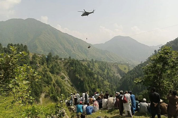 Orang-orang menyaksikan seorang tentara terjun dari helikopter selama misi penyelamatan untuk menyelamatkan siswa yang terjebak di kursi gantung. (FOTO: Al Jazeera/AFP)