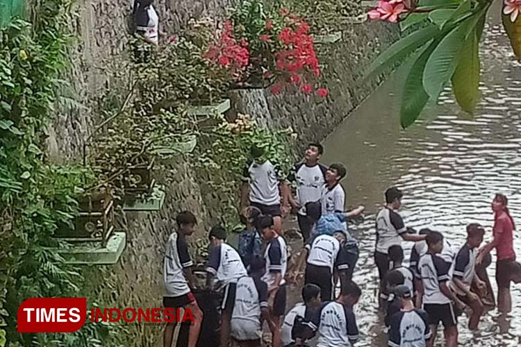 Siswa SMP Widya Sakti nampak mengangkat Sampah yang ada di aliran sungai Buluh. (Foto: Susi/TIMES Indonesia) 