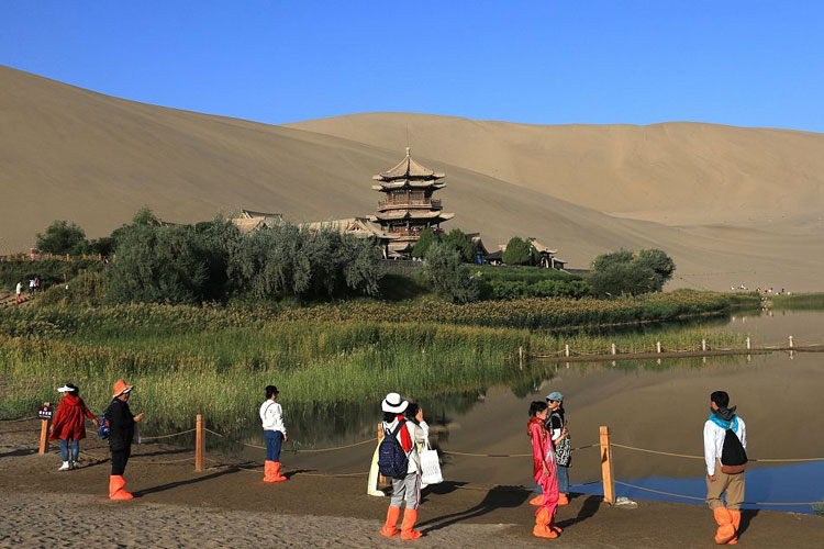 Para wisatawan mengunjungi tempat pemandangan Gunung Mingsha dan Mata Air Mata Air Bulan Sabit di Dunhuang. (FOTO: CFP)