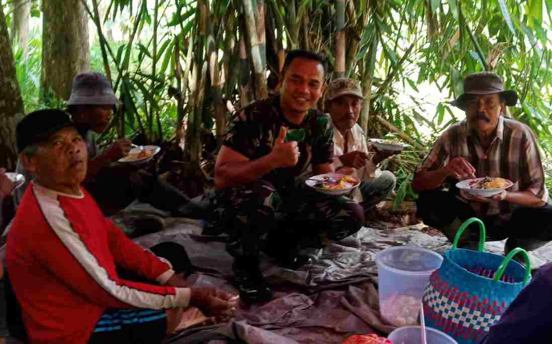 Anggota TNI menikmati makan bersama warga di lokasi TMMD. (Foto: TI PHOTO NETWORK) 