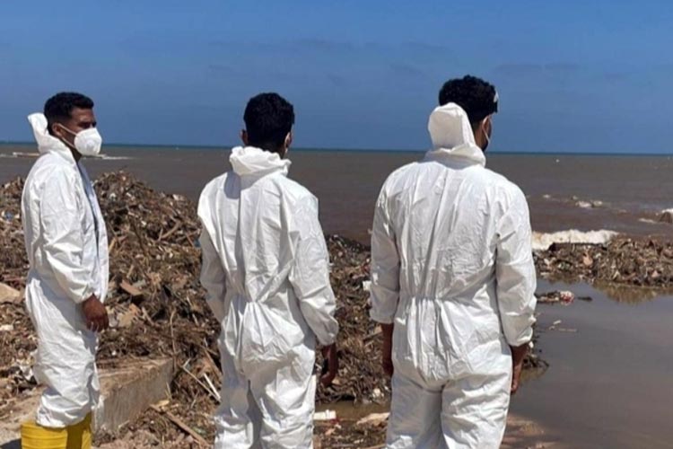 Petugas dengan mengenakan baju khusus tampak memandangi pesisir laut Mediterania dimana masih banyak jenazah terendam di sana menyusul banjir bandang di kota Derna, Libya seminggu lalu. (FOTO: BBC)