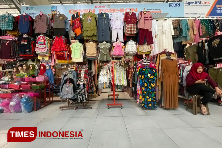 Karyawan kios baju Fasion Gimin di Pasar Besar Ngawi, menghabiskan waktu dengan bermain ponsel. (Foto: M.Miftakul/TIMES INDONESIA)