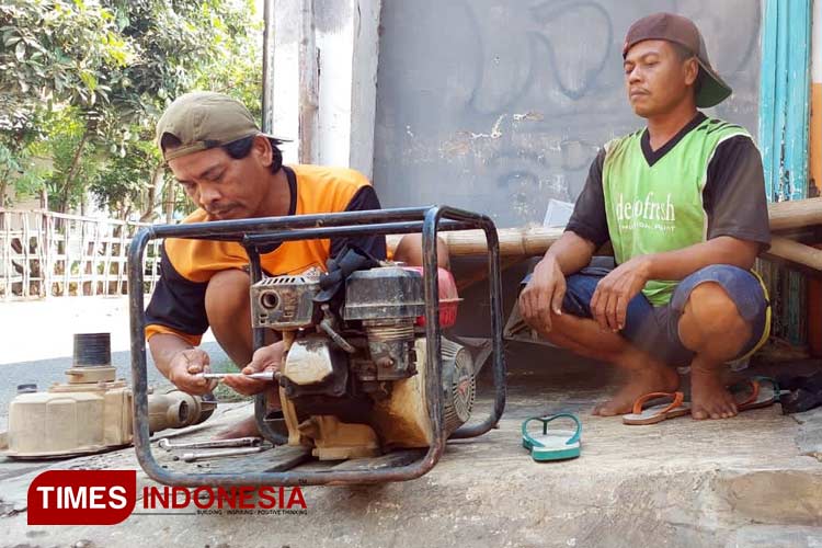 Sulaiman, berkaus oranye, membersihkan mesin pompanya setelah menyelesaikan pengeboran bersama dua rekannya. (Foto: Rizky Putra Dinasti/TIMES Indonesia)